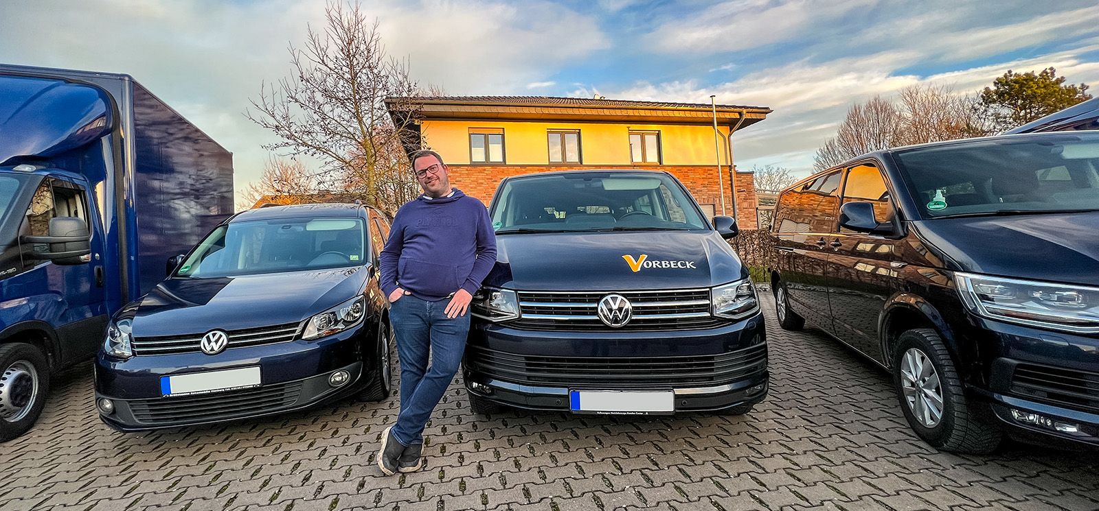 Person lehnt sich gegen einen PKW mit Firmenlogo im Fuhrpark