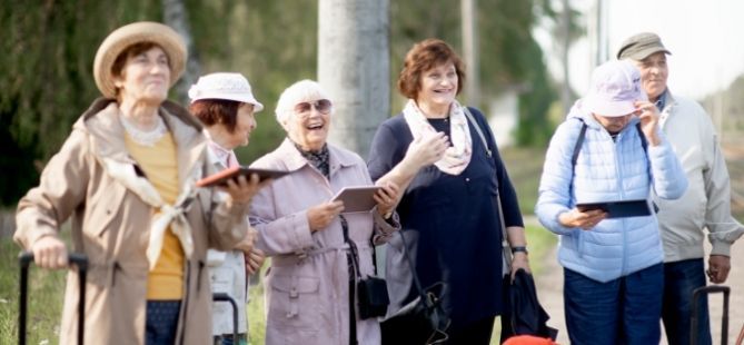 Vier Senioren unterhalten sich im Freien - tragen Koffer mit sich